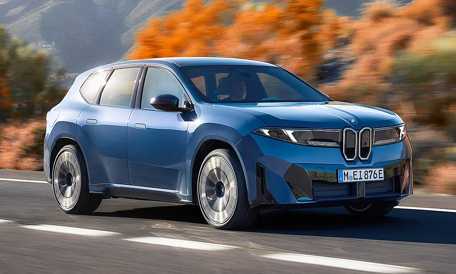 Der BMW iX3 (2026) fahrend von schräg vorne fotografiert.