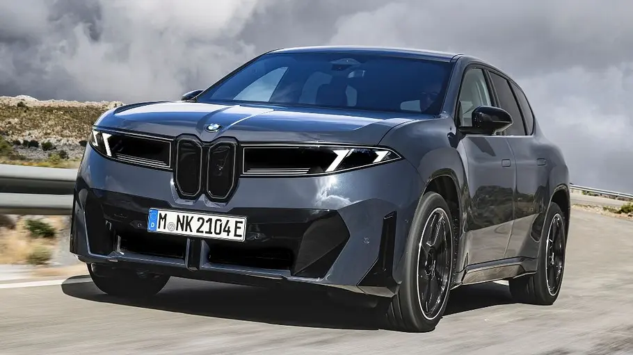 BMW iX3 Ein grauer BMW iX3 fährt auf der Landstraße, von vorne links fotografiert.