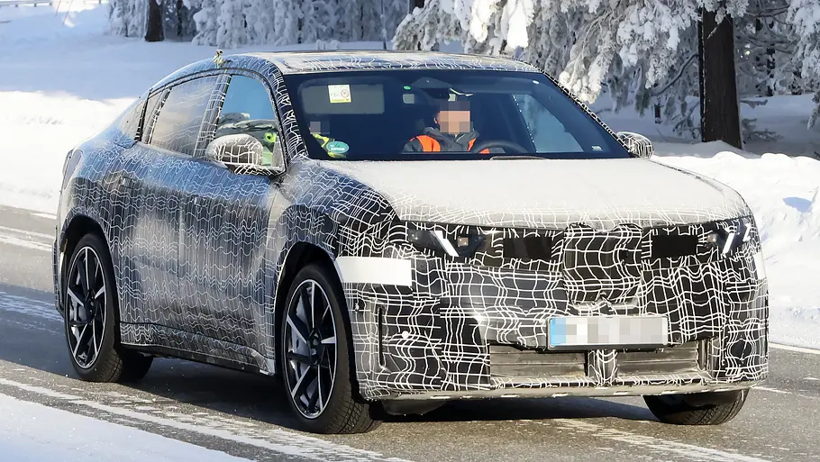 Der BMW iX4 fährt als Erlkönig durch eine verschneite Landschaft, von vorne fotografiert.