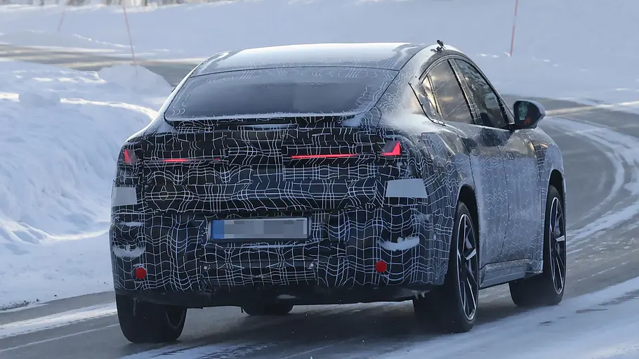 Der BMW iX4 fährt als Erlkönig durch eine verschneite Landschaft, von hinten fotografiert.