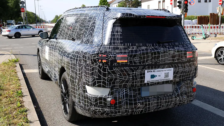 Der BMW iX7 fährt als Erlkönig auf der Straße, von hinten fotografiert.