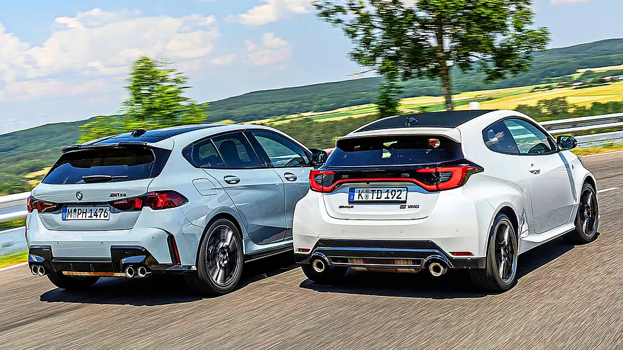 Blick von schräg hinten auf die beiden fahrenden Kompaktsportler BMW M135 und Toyota GR Yaris.
