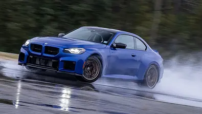 Blauer BMW M2 CS auf nasser Rennstrecke am driften