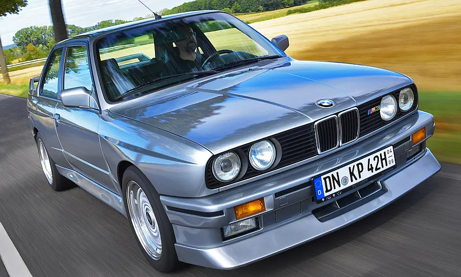 Der BMW M3 E30 fahrend von schräg vorne fotografiert.