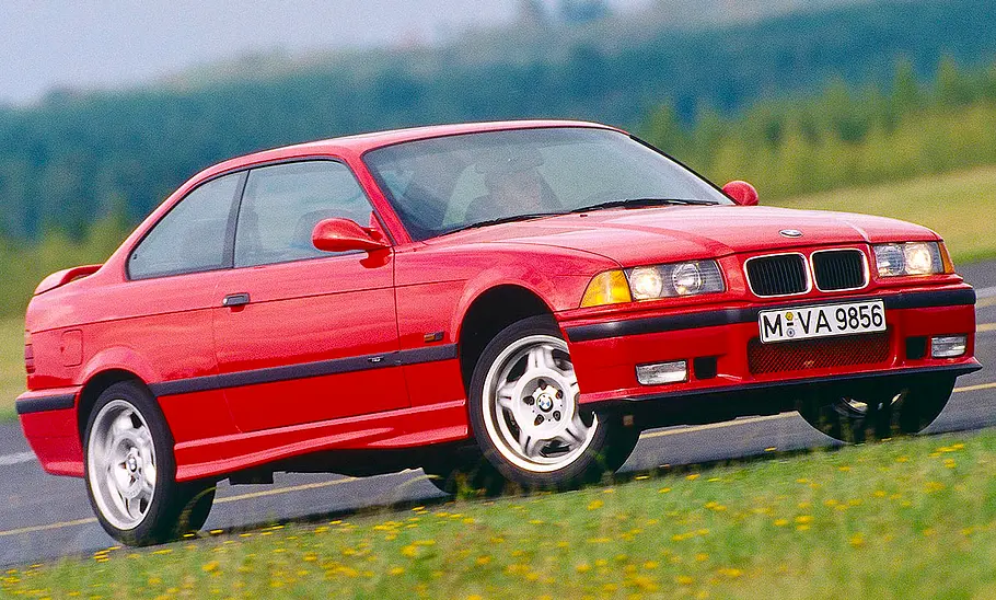 Der BMW M3 (E36) fahrend schräg von der Seite fotografiert.