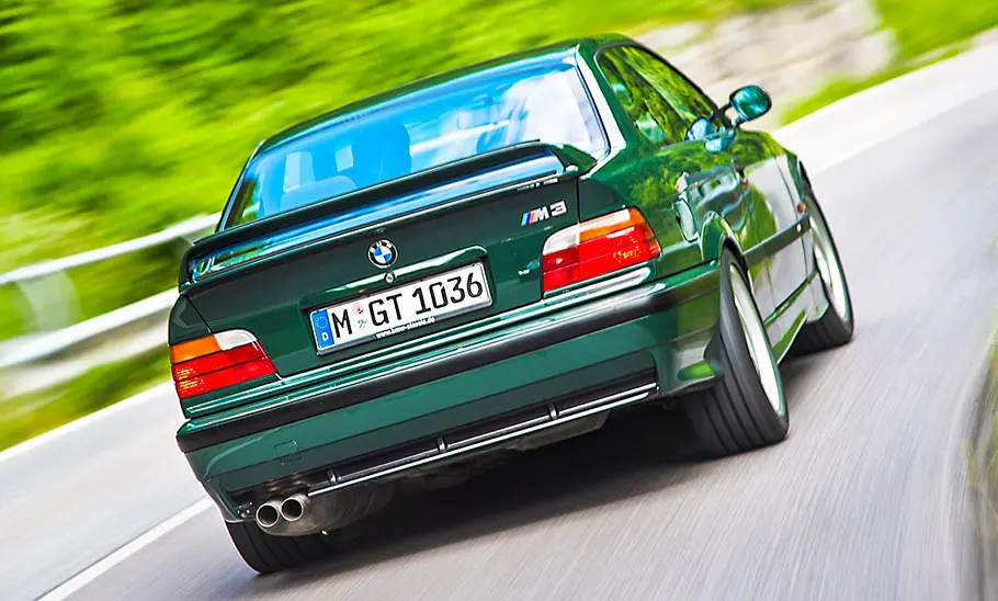 Der BMW M3 GT (E36) fahrend von schräg hinten fotografiert.