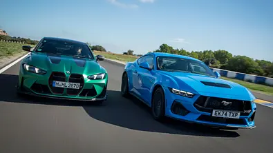 Der BMW M4 CS und der Mustang GT fahren auf einer Rennstrecke, von vorne fotografiert. - Foto: Hardy Mutschler