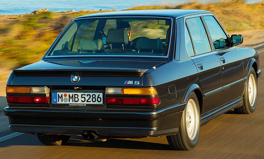 Der BMW M5 (E28) fahrend von schräg hinten