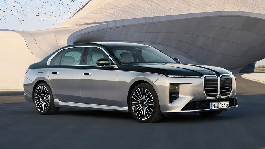Das BMW 7er Facelift steht vor einer amorphen Betonfassade, von vorne rechts fotografiert.
