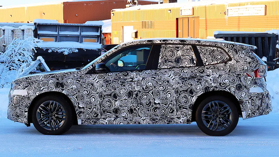 Blick von der Seite auf den fahrenden Erlkönig des BMW X1 Facelift (2026).