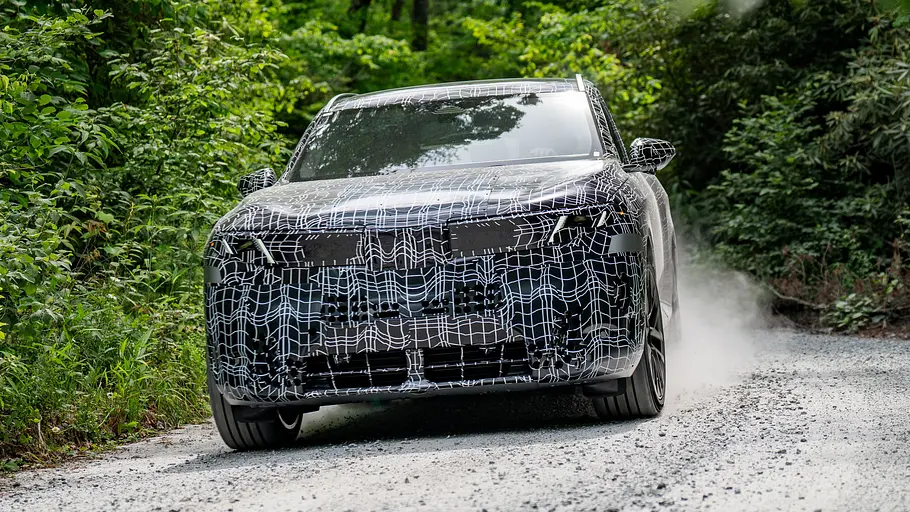 BMW X5 Der BMW X5 fährt als Prototyp durch einen Wald, von vorne fotografiert.