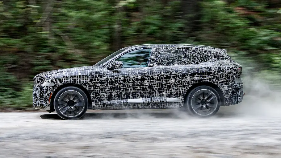 BMW X5 Der BMW X5 fährt als Prototyp durch einen Wald, von links fotografiert.