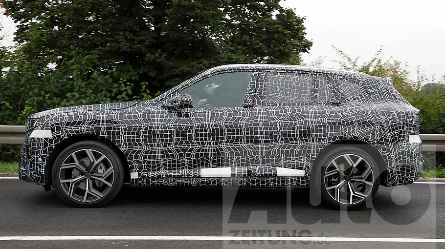 BMW (i)X5 (2026) Der BMW X5 (2026) fährt als Erlkönig auf einer Landstraße, von links fotografiert.