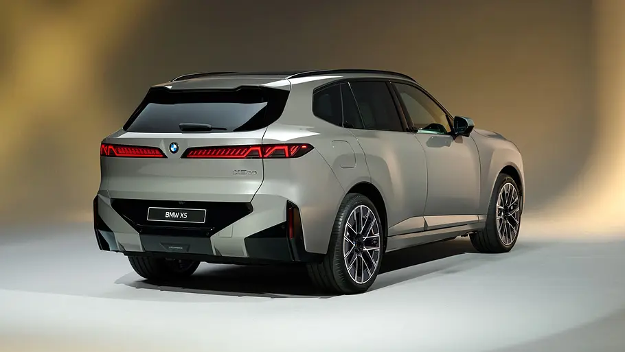 Der BMW iX5 steht in Studioumgebung, von hinten rechts fotografiert.