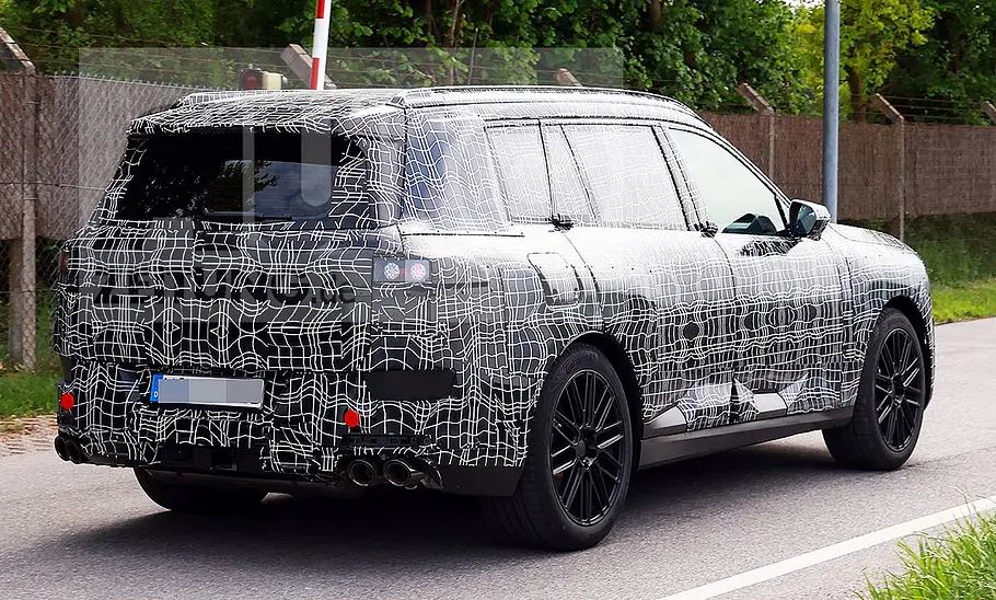 BMW X7 (2027) Blick von schräg hinten auf den fahrenden BMW X7 (2027).