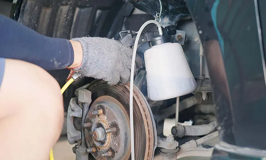 Mechaniker entlüftet Bremse mit einem Bremsenentlüftungsgerät