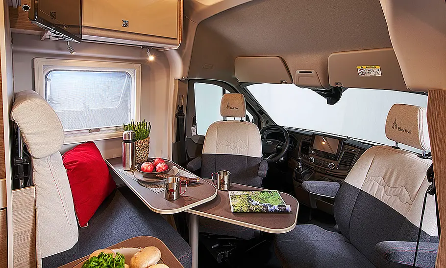 Das Bild zeigt die Sitzgruppe des Bürstner Lineo C 4x4 Black Forest (2024) mit Blick in Richtung Cockpit.