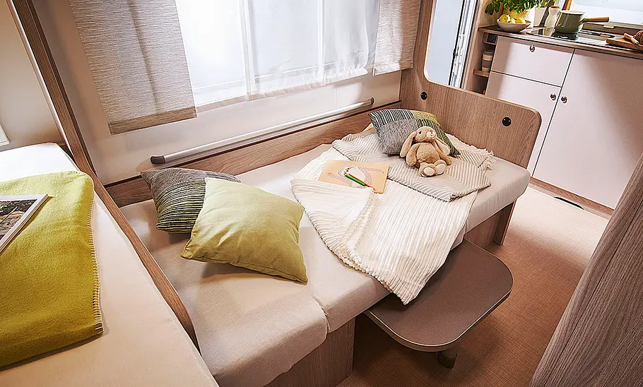 Bürstner Premio Life 425 TS (2024) Das Bild zeigt die zum Einzelbett umgebaute Sitzgruppe des Premio Life 425 TS (2024) mit Blick in Richtung Heck.