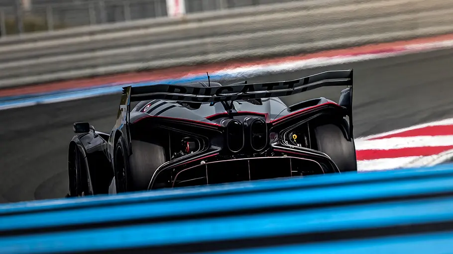 Bugatti Bolide Der Bugatti Bolide fährt auf einer Rennstrecke durch eine Rechtskurve, von hinten fotografiert.
