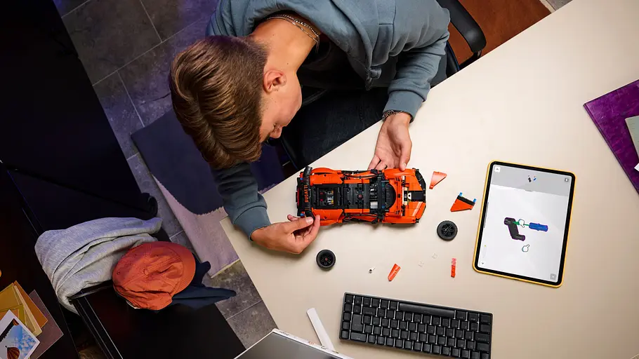 Bugatti Lego Neuheiten Aus der Vogelperspektive: Ein Teenager baut den Chiron Pur Sports von Lego Technic an einem Schreibtisch auf.