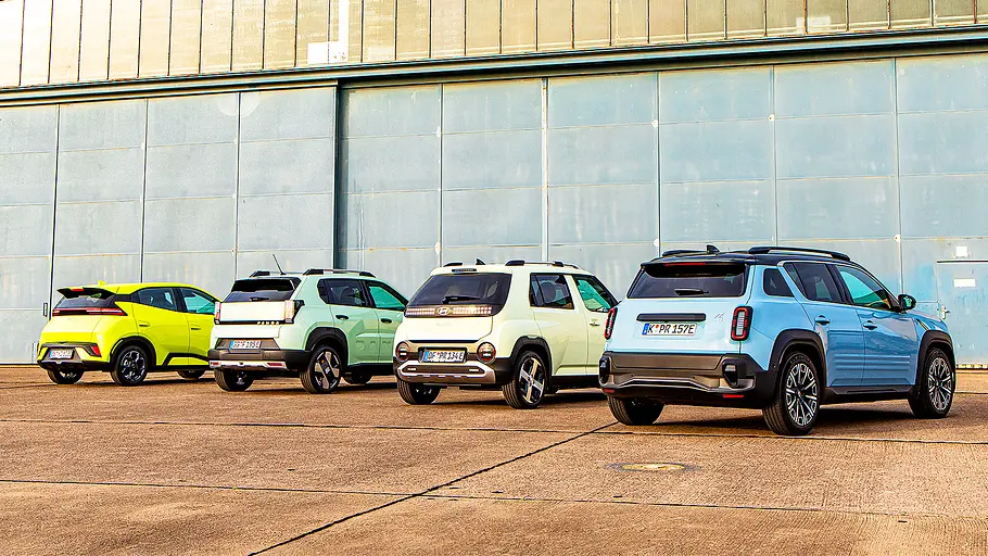 Blick von schräg hinten auf die vier E-Kleinwagen BYD Dolphin Surf, Fiat Grande Panda, Hyundai Inster und Renault 4.