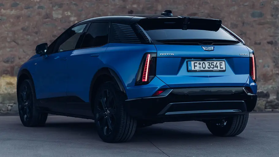 Der Cadillac Optiq (2026) steht vor einer Mauer. Von hinten schräg fotografiert.