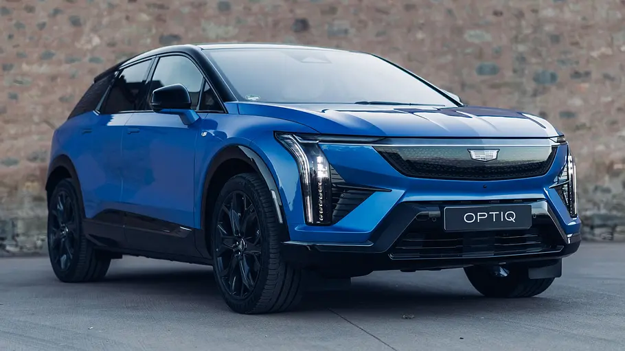 Der Cadillac Optiq (2026) steht vor einer Mauer. Von vorne schräg fotografiert.