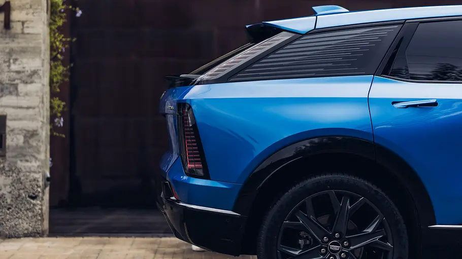 Der Cadillac Optiq (2026) steht vor einem Tor. Der geschlossene Kofferraum wurde seitlich fotografiert.