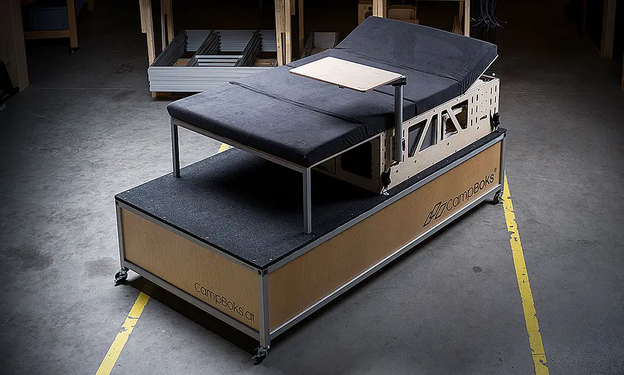 Das Bild zeigt das CampBoks Campingbox-Modul außerhalb eines Fahrzeugs. Das Modul befindet sich im Bettumbau.