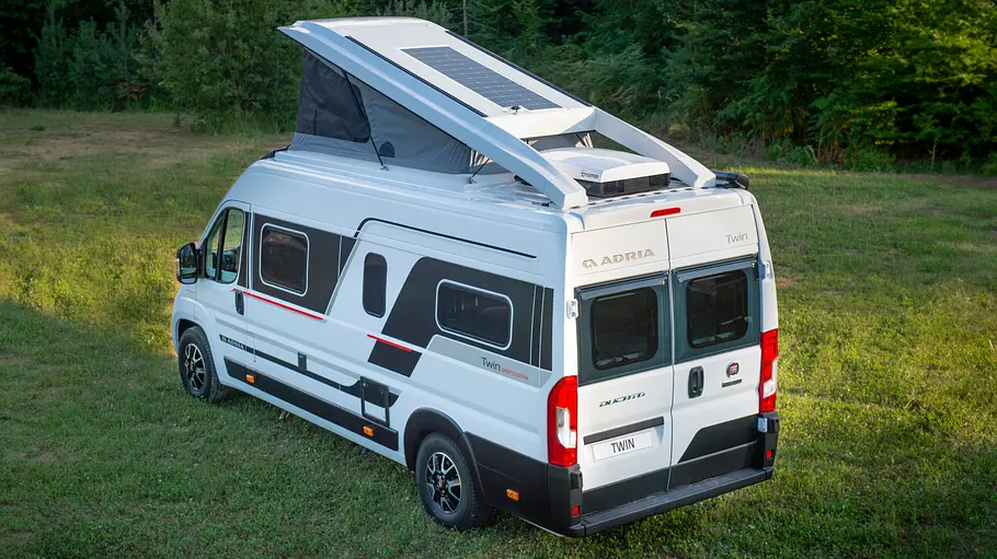 Campervans mit Aufstelldach Der Adria Twin Sports stehend von schräg hinten links mit geöffnetem Aufstelldach.