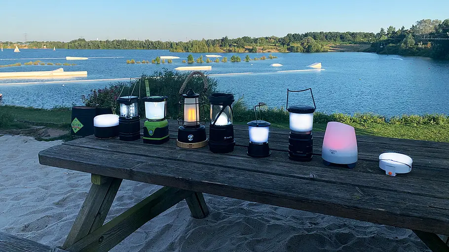 Überblick über die Testlampen im Campinglampen-Test. Die stehen auf einem Tisch nebeneinander.