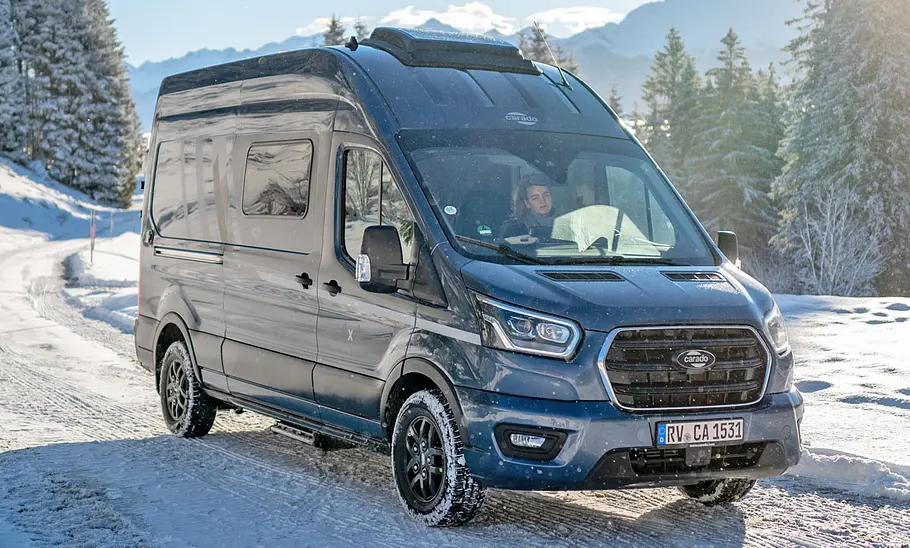 Der Carado CV590 4x4 ist mit Ansicht von schräg vorne fahrend im Schnee zu sehen.