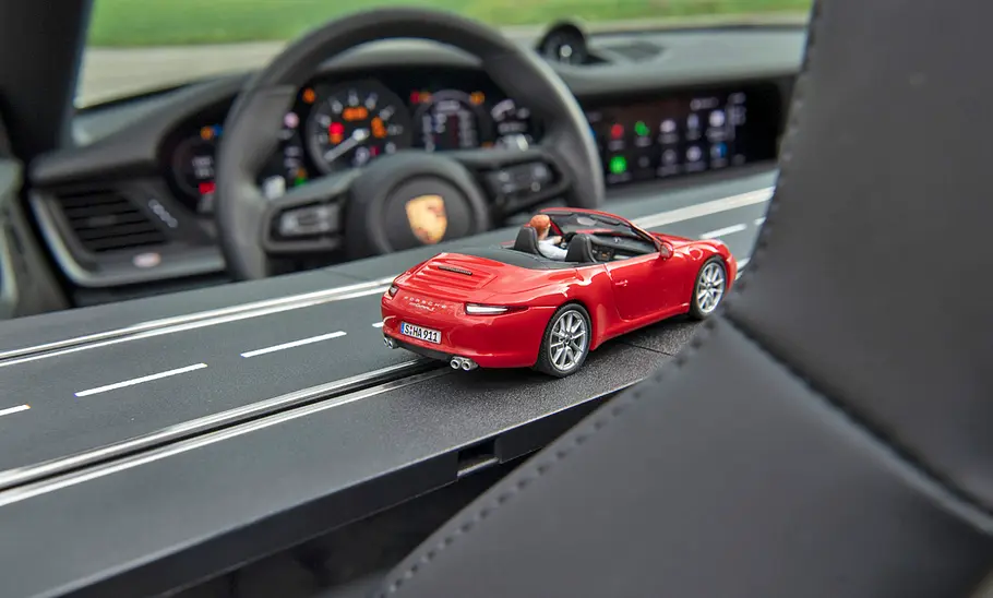 Der Carrera-Bahn Porsche 911 fährt auf der Schiene ins Cockpit des echten Porsche 911 Cabrio.