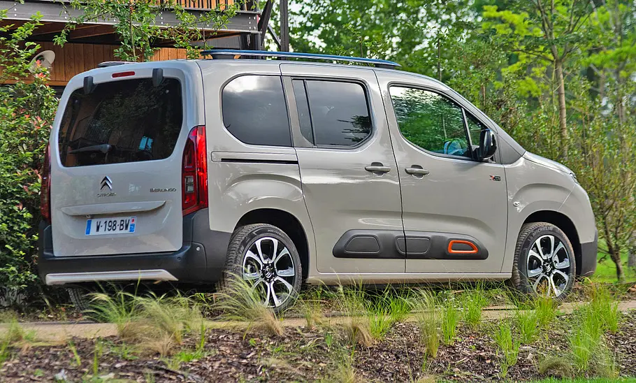 Citroën Berlingo steht auf einer Straße im Grünen, Ansicht von schräg hinten rechts.