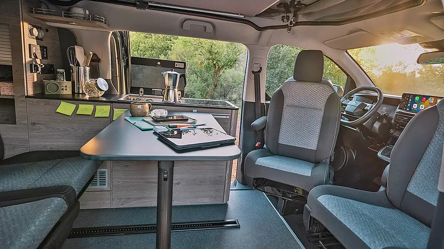 Blick in den Wohraum des Citroën Holidays durch die Schiebetür auf den Klapptisch und die Sitze.