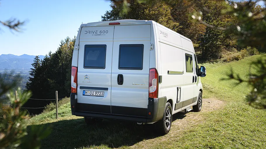 Der Clever Vans Drive 600 statisch von schräg hinten rechts auf einer Wiese vor einem Waldstück.