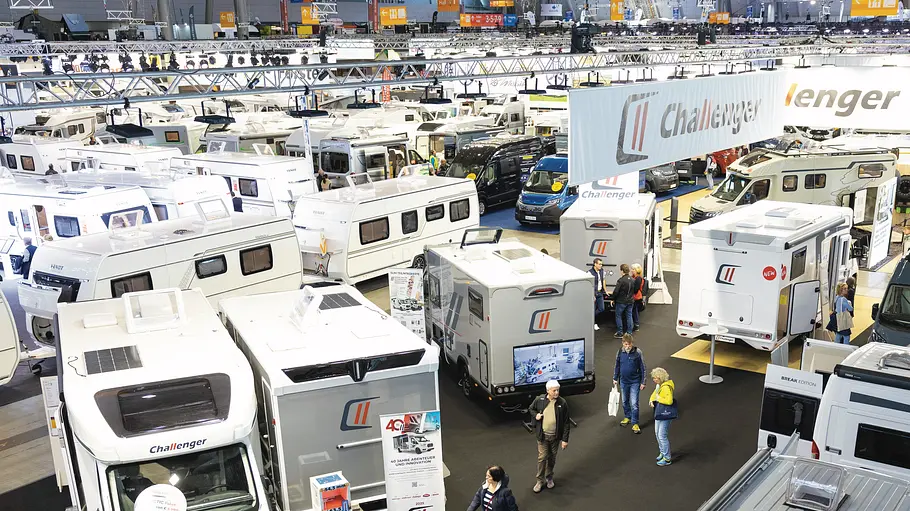 Blick aus leicht erhöhter Position über eine Halle der Messe Stuttgart, in der während der CMT 2025 Campingfahrzeuge verschiedener Hersteller gezeigt werden.