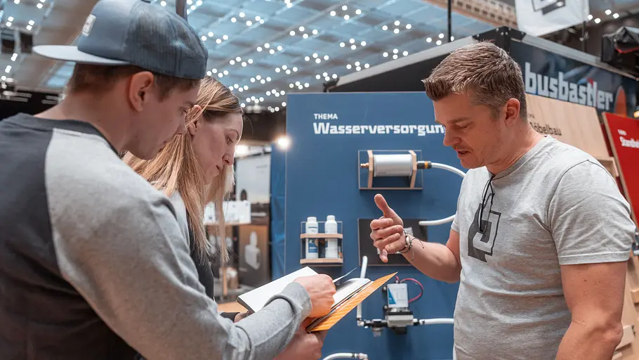 Ein Paar lässt sich auf der CMT in der Zubehör-Halle der Messe von einer fachkundigen Person zur Wasserversorgung im Camper beraten.