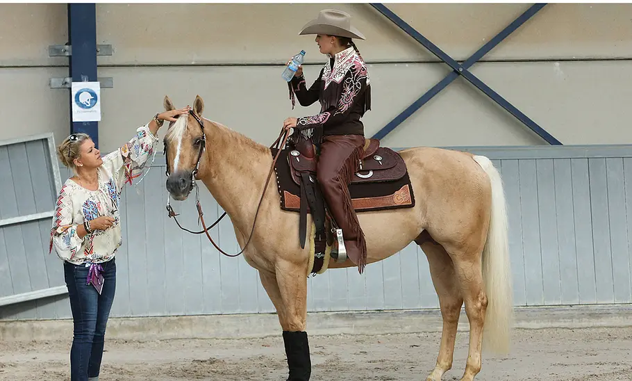 Gina Schumacher sitzend auf einem Pferd, davor steht Corinna Schumacher und streichelt das Pferd.