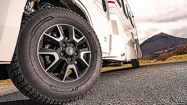 Das Bild zeigt ein Wohnmobil von schräg unten links fotografiert. Der Fokus liegt auf dem leicht eingeschlagenen Vorderrad, auf dem ein Reifen für Wohnmobile installiert ist. - Foto: AUTO ZEITUNG
