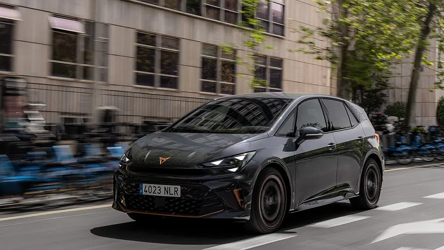 Cupra Born Facelift 2026 Die fahrdynamische Aufnahme zeigt den Cupra Born (2026) vor einer urbanen Kulisse von schräg seitlich.