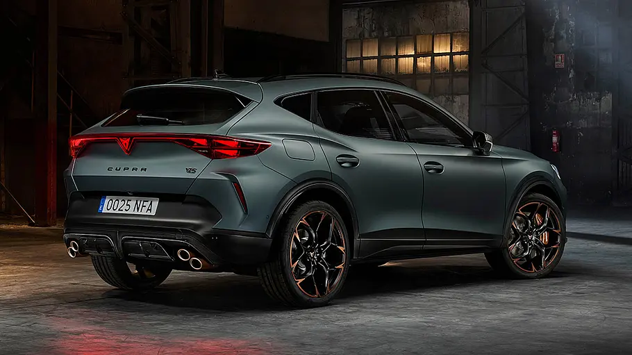 Der Cupra Formentor VZ5 steht in einer dunklen Halle, fotografiert von schräg hinten.