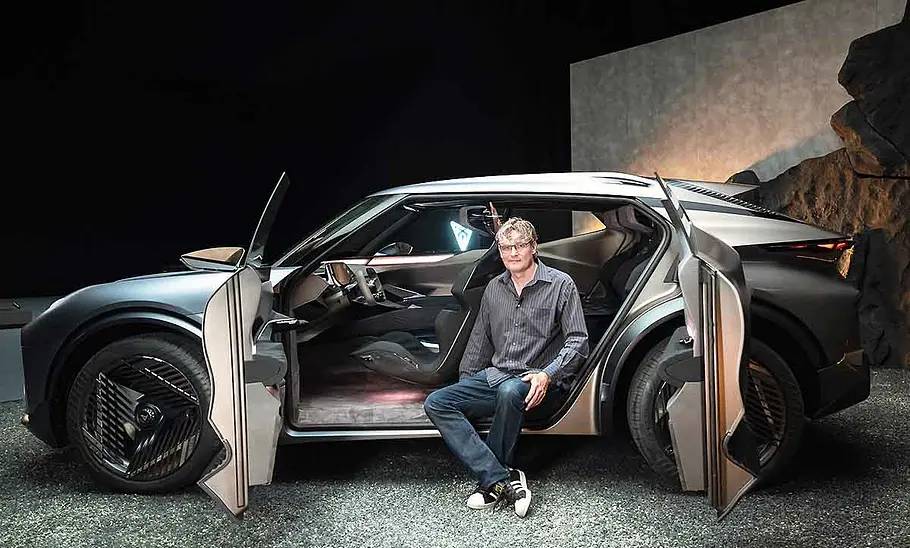 Ein Redakteur der AUTO ZEITUNG sitzt auf dem Boden des Innenraums der IAA-Konzeptstudie Cupra Tindaya (2025) bei geöffneten gegenläufigen Türen.