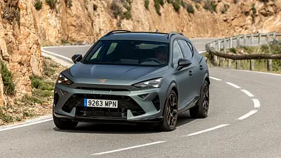 Der Cupra Formentor fährt durch eine S-Kurve auf einer Landstraße. Links im Bild ist eine Steinklippe zu sehen. - Foto: Cupra