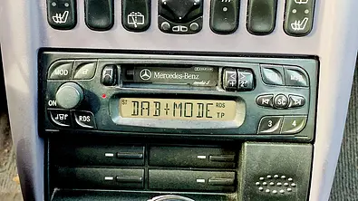 Ein älteres Autoradio im Armaturenbrett, das den DAB+ Mode anzeigt. - Foto: Holger Ippen