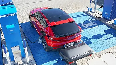 Das Bild zeigt einen Volvo C40 Recharge Pure Electric von schräg hinten links an einer Ladesäule für Elektroautos. Das Foto ist aus einer leicht erhöhten Position aufgenommen. Eine Heckbox ist auf der Anhängerkupplung angebracht. - Foto: Thomas Starck