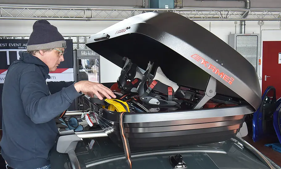 Kamei Fosco im Dachboxen-Test Ein Tester beim Beladen der Dachbox Kamei Fosco, fotografiert von der Seite.