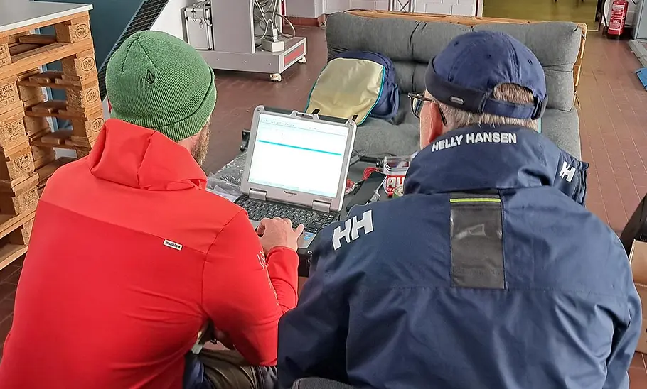 Dachboxen-Test Zwei Tester sitzen vor einem Laptop und werten Daten des Dachboxen-Tests aus.