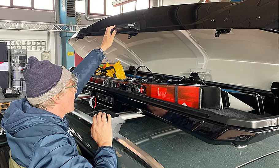 Dachbox Thule Vector L beim Beladen mit Tester, fotografiert von schräg hinten.