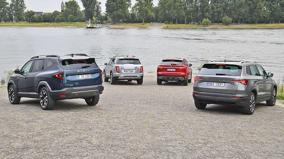 Dacia Bigster, KGM Torres, MG HS und Skoda Karoq stehen in einer Formation an einem Pier, von hinten fotografiert.